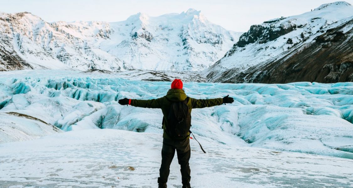 hiker standing in front of a glacier in iceland