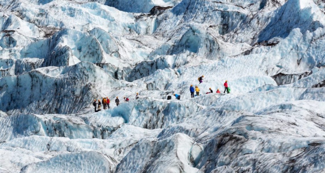 hikers walk on a glacier in iceland
